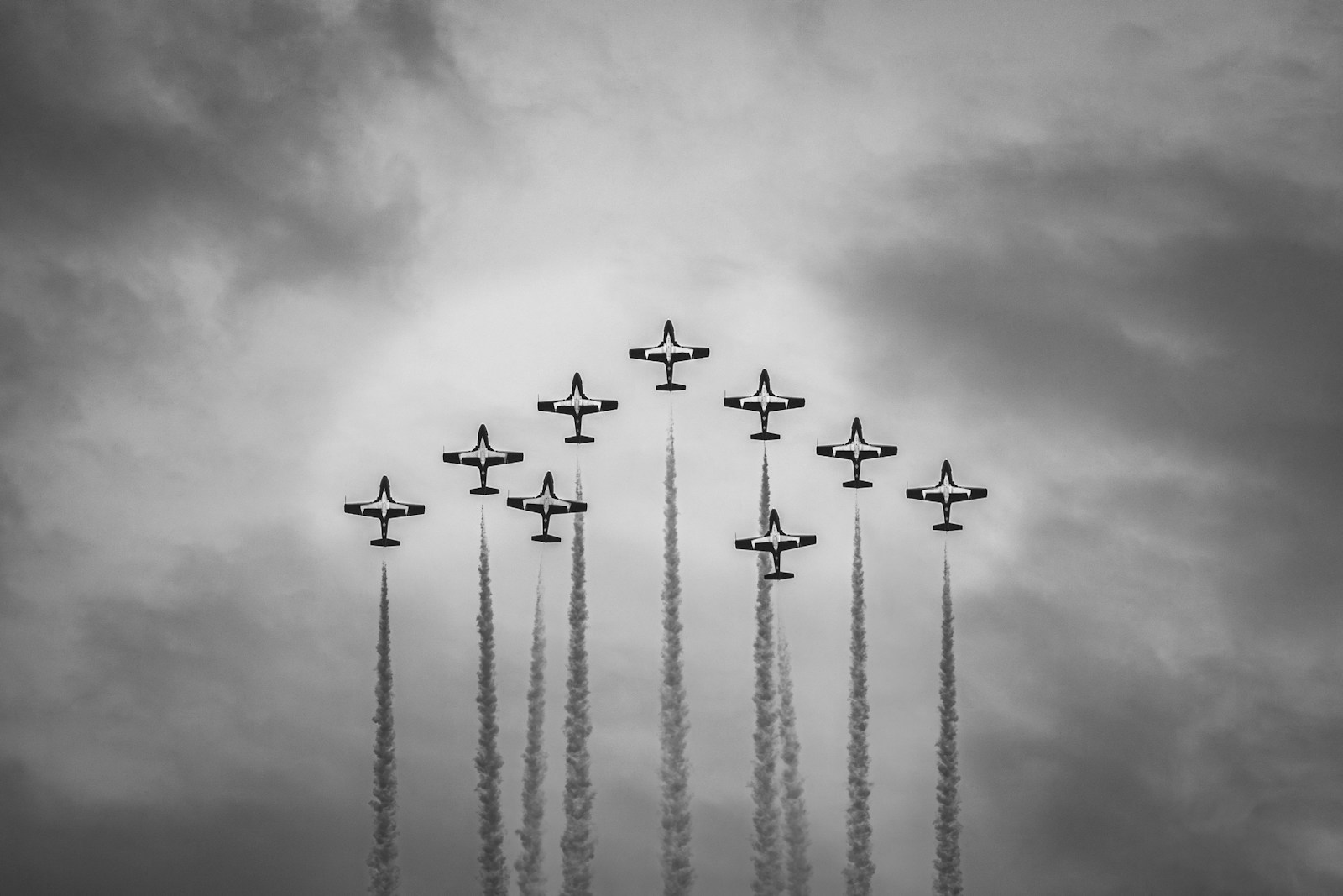 Planes flying in formation against a cloudy sky